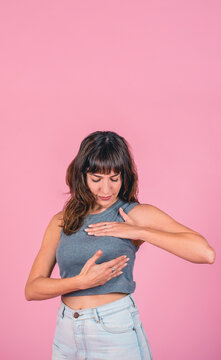 Woman doing a Breast Self-Exam checking up breast changes over pink background. Copy space