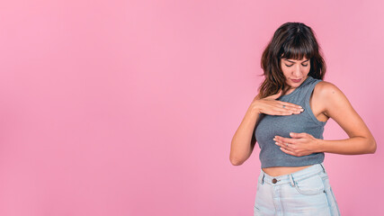 Woman doing a Breast Self-Exam over pink background. Copy space