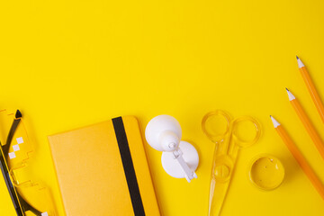 Top view of different stationery supplies on the bold yellow background,frame with negative space.