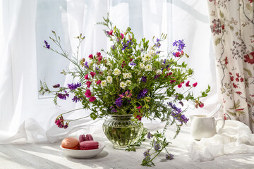 Still life with a bouquet of wild flowers on the windowsill on a sunny day