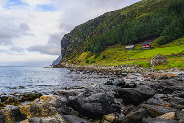 Serene Morning at the Rocky Shores of Maløy, Norway with a Red House and Towering Cliffs