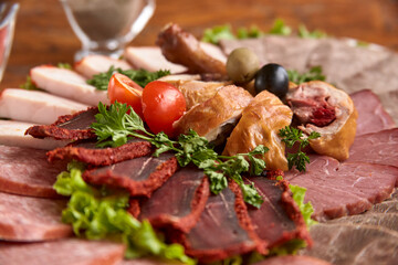 Part of plate with cold cuts with choice - salami, pieces of sliced ham, sausage, chicken, qazi horse meat, tomatoes on salad, close-up, shallow depth of field