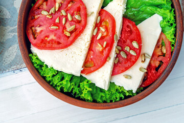 Top view: salad of pickled cheese, tomatoes and roasted sunflower seeds