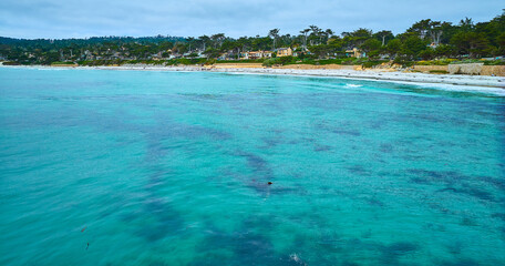 Gorgeous teal blue ocean water with kelp below waves aerial at Carmel Beach with sandy shore