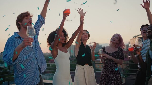 Multiracial coworkers throwing confetti at rooftop party