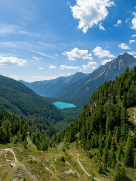 Aerial view of alpine lake Lago di Anterselva (Antholzer See) as seen from Passo Stalle (Staller Pass) in a Dolomite mountain valley with green pine forest 