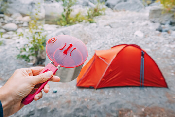 camping food - metal pot on the background of a tent in wild camping. Hiking cookware and tableware