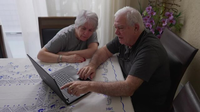 Seniors Interacting with Modern Technology, Using Laptop at Home, older husband and wife browsing internet
