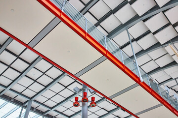 Orange edged walkway with person walking next to railing and white ceiling tile view