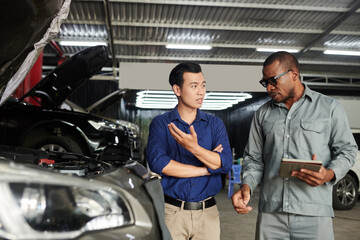 Car owner telling mechanic what problems he has with his car