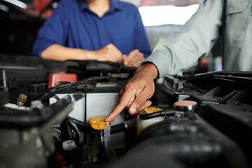 Mechanic explaining client what parts of automoble he fixed before accepting payment