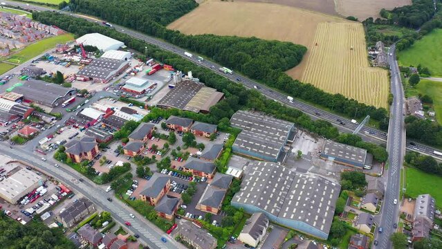 Aerial footage of the town of Morley in the City of Leeds metropolitan borough, in West Yorkshire, England showing a main road motorway and houses with businesses in the summer time.