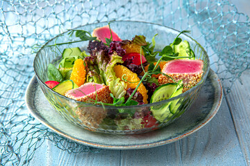 Salad with fresh tuna on a blue background. Mediterranean Kitchen. Sea mood menu.