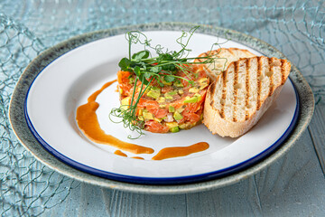 Salmon and avocado tartare on a blue background. Mediterranean Kitchen. Sea mood menu.