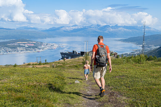 Little girl and his dad hiking on the top of the mountain with Tromso city on the underneath