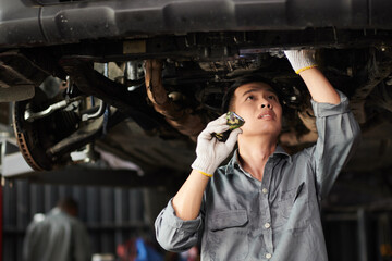 Mechanic inspecting suspended vehicle for leakages