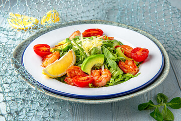 Salad with shrimp and avocado on a blue background. Mediterranean Kitchen. Sea mood menu.