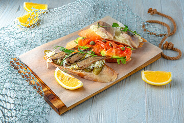 Bruschetta with sprats, salmon, herring on a blue background. Mediterranean Kitchen. Sea mood menu.