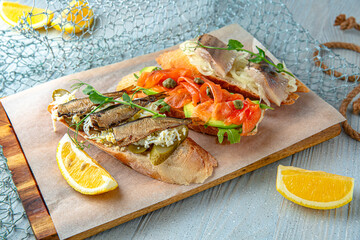 Bruschetta with sprats, salmon, herring on a blue background. Mediterranean Kitchen. Sea mood menu.