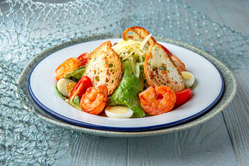 Salad with shrimp and avocado on a blue background. Mediterranean Kitchen. Sea mood menu.