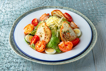 Salad with shrimp and avocado on a blue background. Mediterranean Kitchen. Sea mood menu.