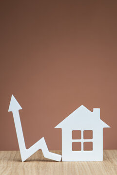 Increasing the cost of renting a home. Banner with a model of a white house and a graphic arrow pointing up close-up on a brown background. Vertical photo with copy space.