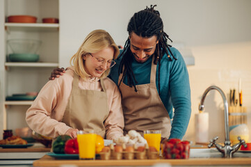 A happy interracial married couple in love is preparing delicious homemade food together.