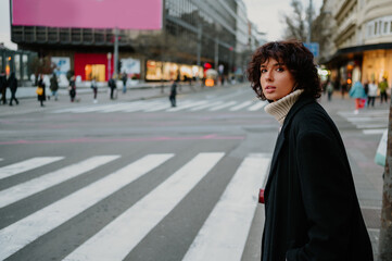 Pretty girl looking down the street while crossing it at the pedestrian crossing