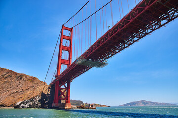 Underside view of Golden Gate Bridge from choppy San Francisco Bay waters - obrazy, fototapety, plakaty