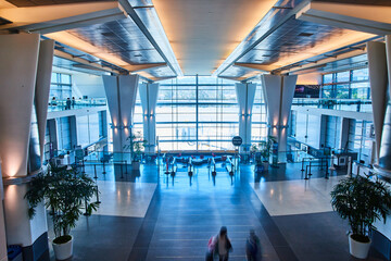 Open airport interior with blue and cream lighting and bright light from windows