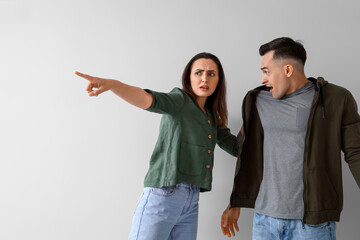 Young couple quarreling on light background