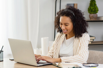 African American woman with headset and laptop, call center or customer support worker. Female advisor, consulting a client online