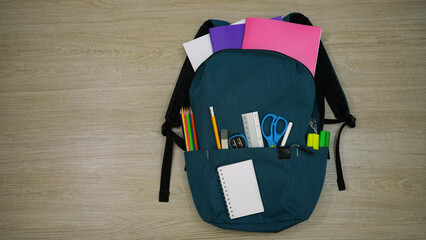 Colorfull school supply in school bag on grey table