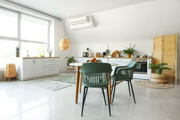 Interior of modern kitchen with white counters and dining table