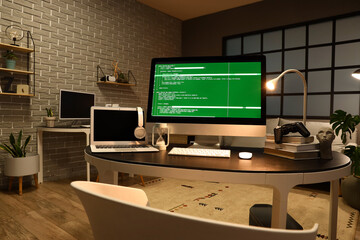 Programmer's workplace with computer, laptop and glowing lamp in dark office