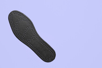 Black orthopedic insole on lilac background