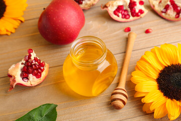 Jar of honey, pomegranate, apple and sunflower for Rosh Hashanah celebration (Jewish New Year) on wooden table