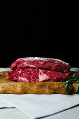 Raw organic beef meat with rosemary, seasonings, salt and red pepper  on wooden cutting board