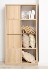 Wooden bookcase with pillows and decor in light room