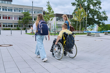 Children going to school, boy in wheelchair and girls, rear view