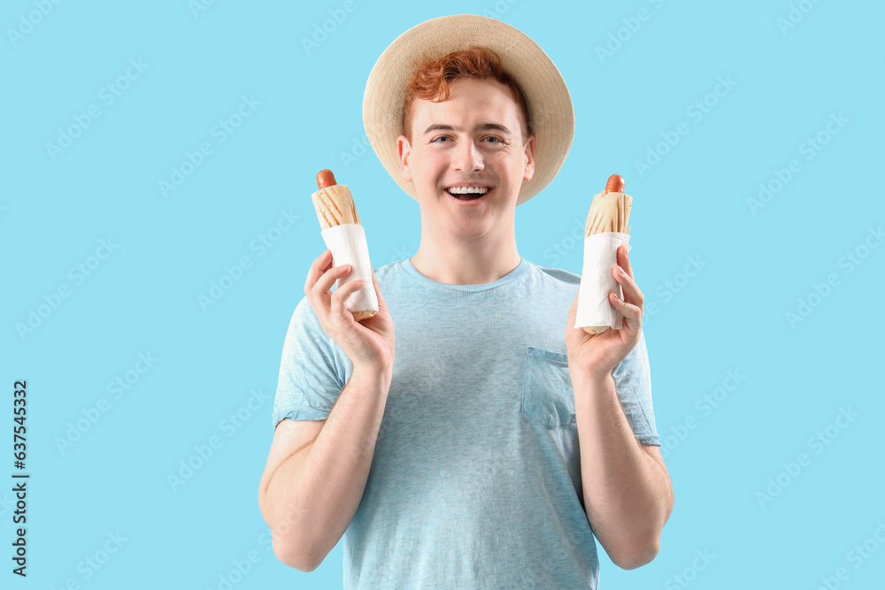 Canvas Prints Young man with tasty hot dogs on light blue background