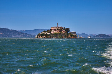 Choppy waters around Alcatraz Island with distant tour boat and mountains