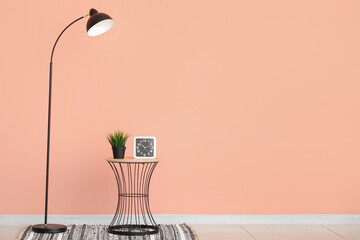 Standard lamp and houseplant on small table near pink wall