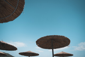 Minimalist Beach Serenity: Straw Umbrellas Against Azure Sky