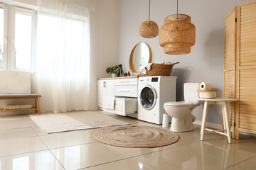 Interior of light restroom with ceramic toilet bowl and washing machine