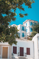 Vibrant buildings in Skopelos town, Greece, painted in traditional Greek hues of blue, maroon, and yellow, set against a clear blue sky.