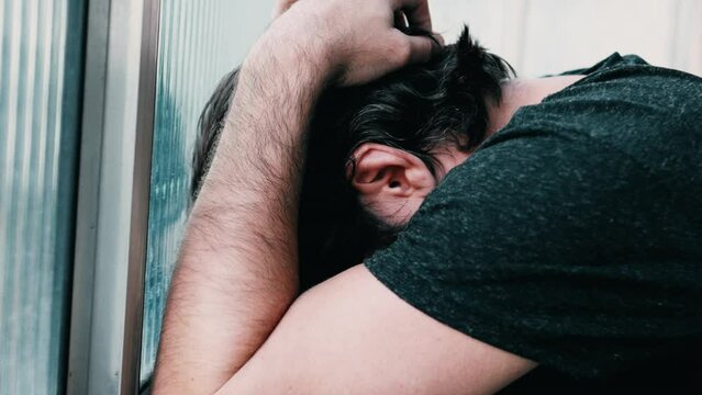 Person suffering from emotional pain covering face in shame. Young man in despair and loneliness