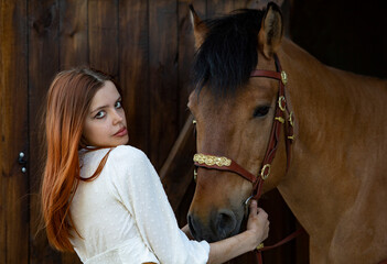 Country girl posing with horse in stable