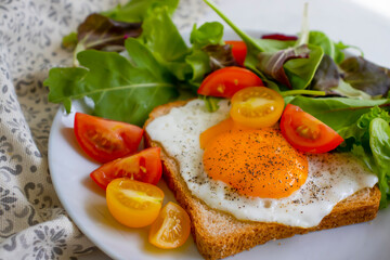 Bread with fried egg, tomatoes, lettuce