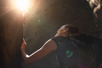 Out of the darkness and into the light. Female hiker leaving a dark cave looking up to the light 